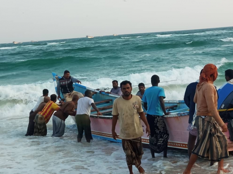 Yemeni and Somali fishermen bring a skiff in to the beach.
