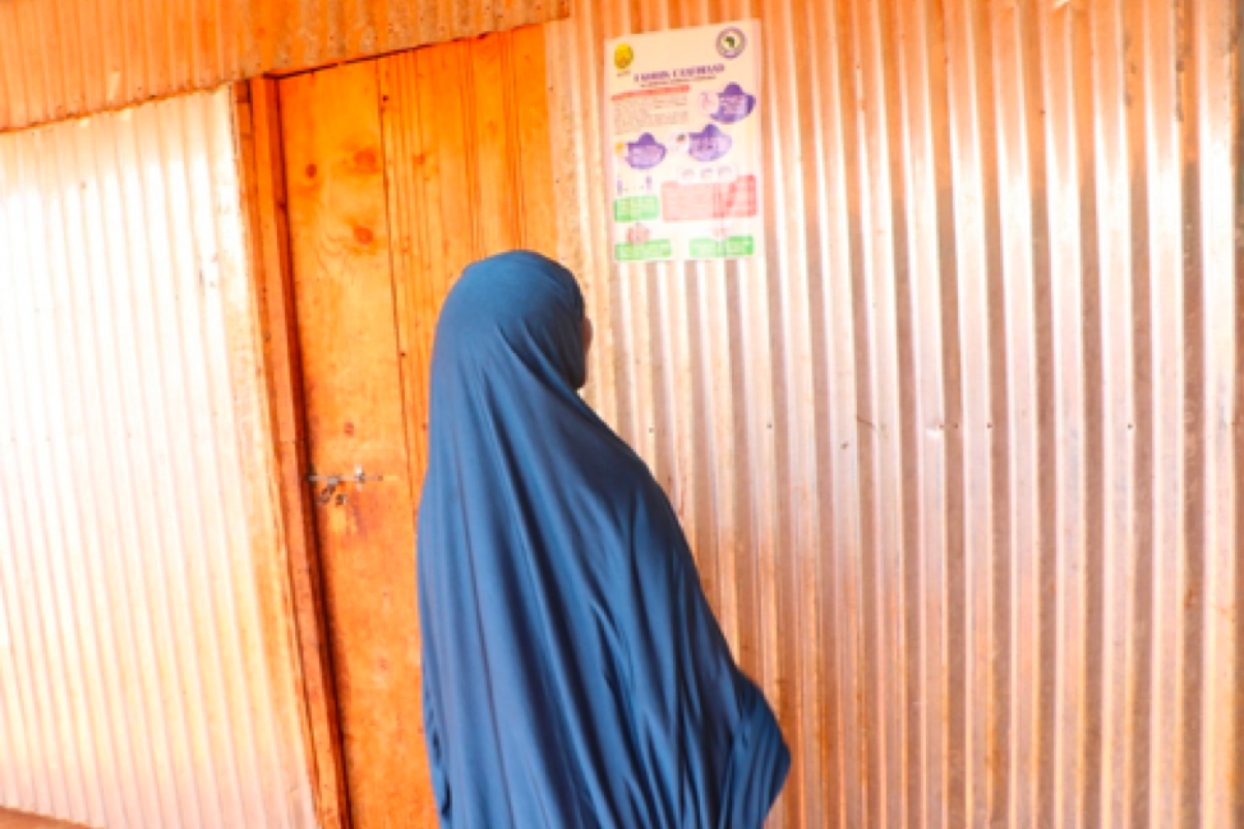 Woman in Somaliland reading a Covid-19 awareness sticker. © SOYDAVO
