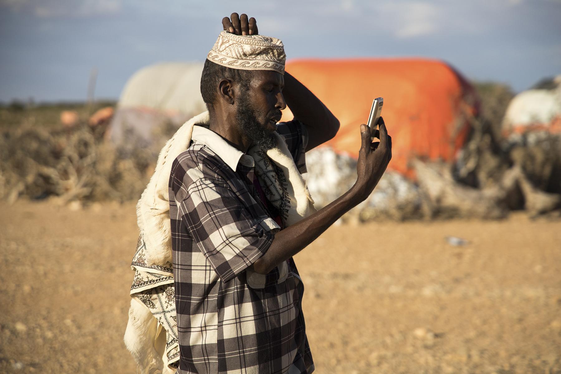 A man checks the network reception on his phone in the village of Faleyare in Northern Somalia.